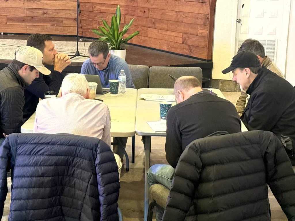 Leaders praying and working together around tables