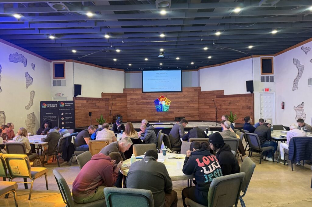 Participants pray and reflect together around tables at a Greater Austin Mission Society gathering.